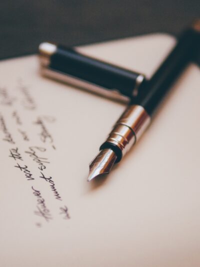 A fountain pen lies on a handwritten note