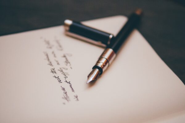 A fountain pen lies on a handwritten note