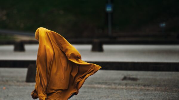 Profile of a woman wearing a billowing orange head scarf.