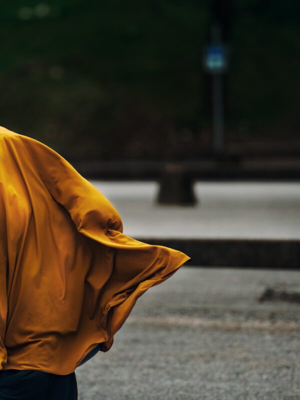 Profile of a woman wearing a billowing orange head scarf.