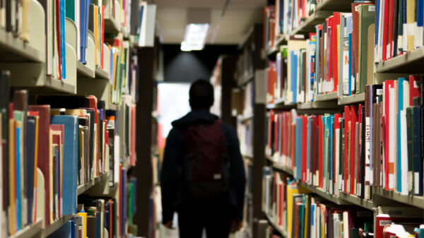 A student walks through shelves of books in a school library