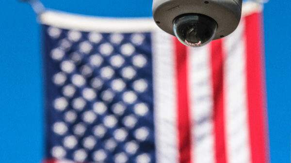 Background: the american flag. Foreground: a security camera