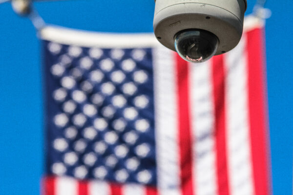 Background: the american flag. Foreground: a security camera