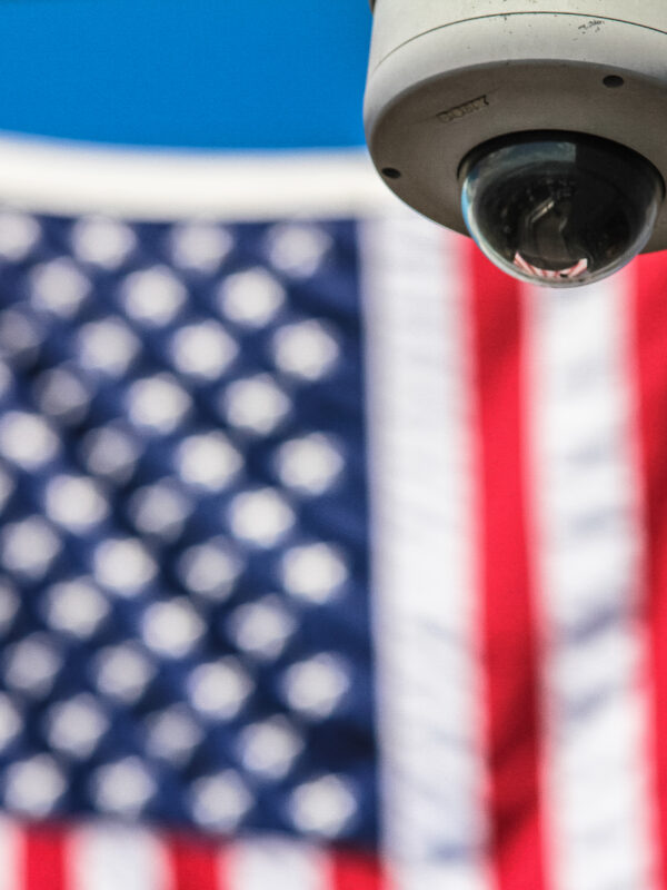Background: the american flag. Foreground: a security camera