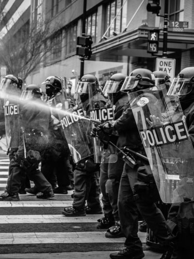 Police in riot gear spray a protester with water