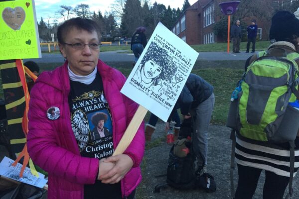 Irene Kalonji holds a sign with her son's face on it at a memorial event