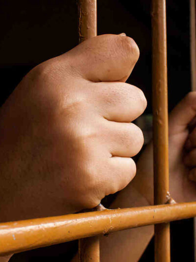 hands grasping jail bars