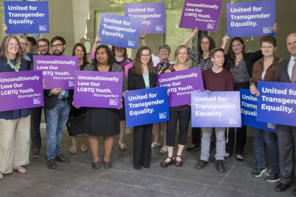 advocates outside court holding signs for transgender equality