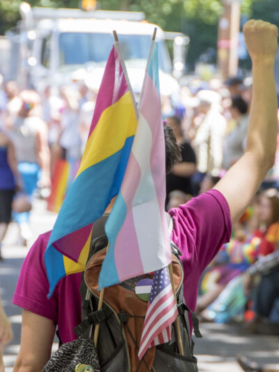 pride marcher with trans pride flag and fist upraised