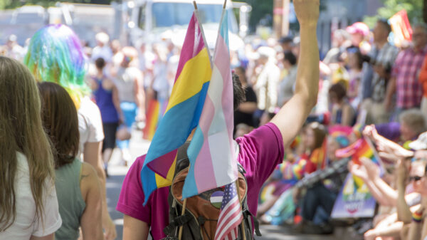 pride marcher with trans pride flag and fist upraised