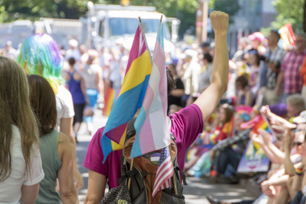 pride marcher with trans pride flag and fist upraised