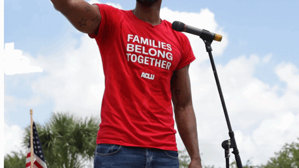 rally speaker with t-shirt that reads "families belong together"