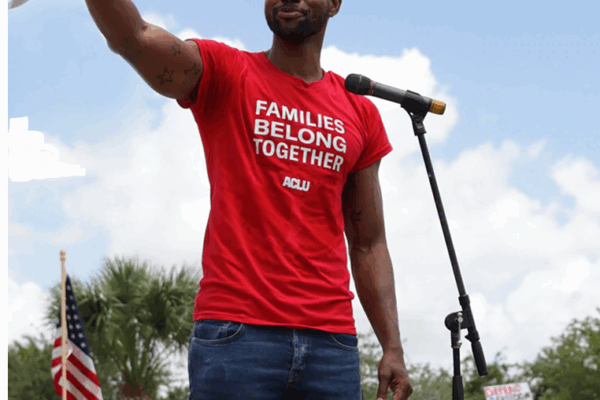 rally speaker with t-shirt that reads "families belong together"