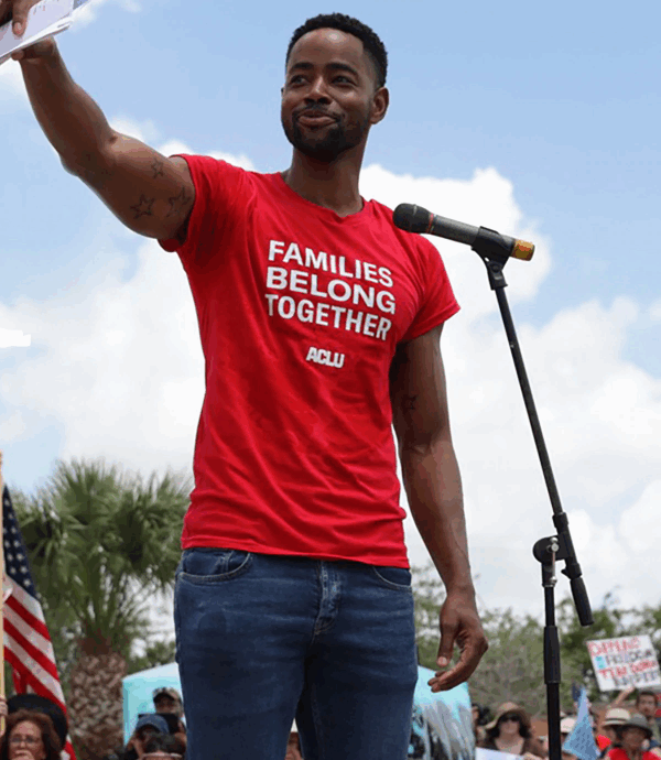 rally speaker with t-shirt that reads "families belong together"
