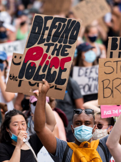 Protestors march down Pennsylvania Avenue holding signs that read “Defund the Police” and “Stop Police Brutality” among other signs.