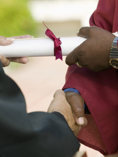 A black man receiving his diploma and giving a handshake.
