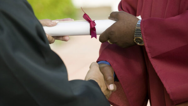 A black man receiving his diploma and giving a handshake.