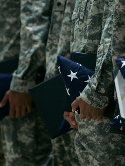 U.S. Army soldiers holding certificates and folded U.S. flags during a ceremony.