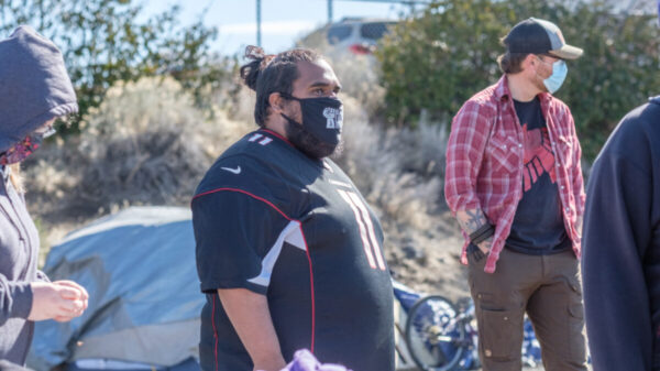 Image of a person wearing a mask in front of a tent.