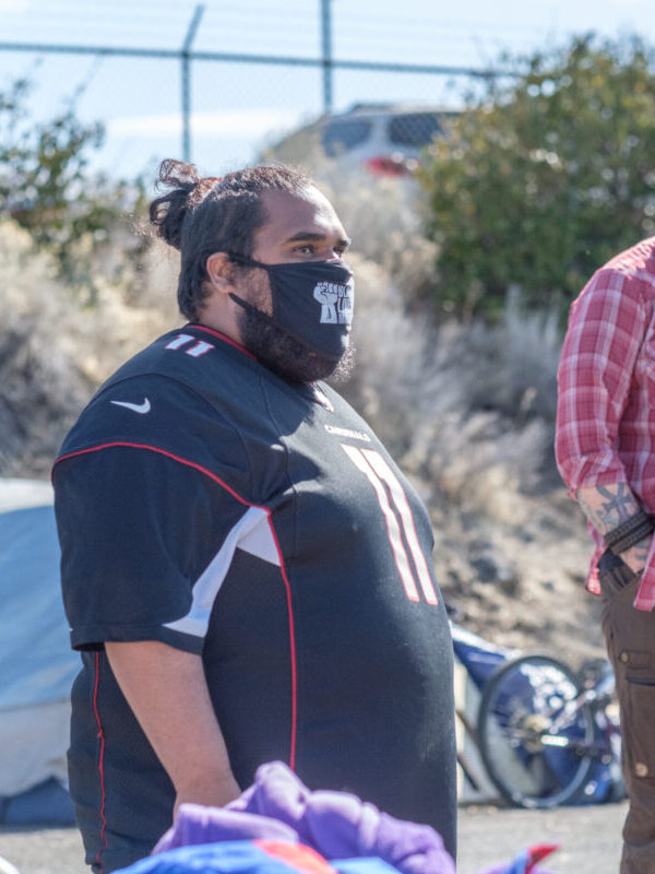 Image of a person wearing a mask in front of a tent.