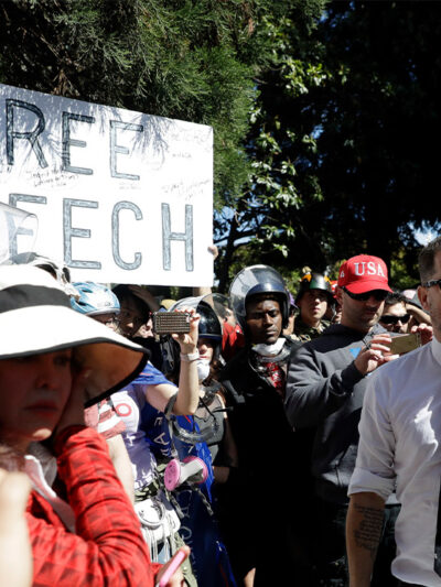 Man speaking to a crowd, rallying for support at a free speech protest.