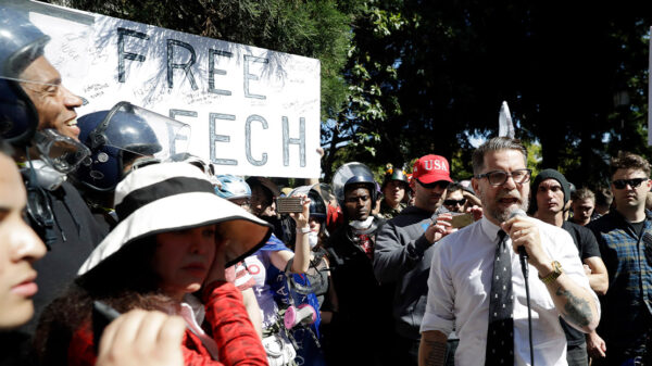 Man speaking to a crowd, rallying for support at a free speech protest.
