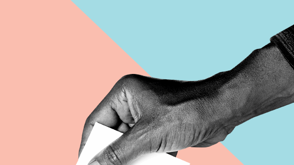 Hand placing ballot in box.