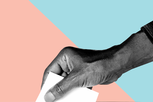 Hand placing ballot in box.