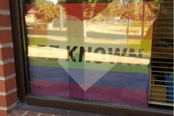 Rainbow sign with a heart and the words “Be Known” in Chelsea Shott's classroom window