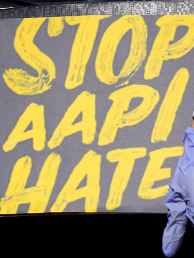 Woman holds a sign stating “Stop AAPI Hate.”