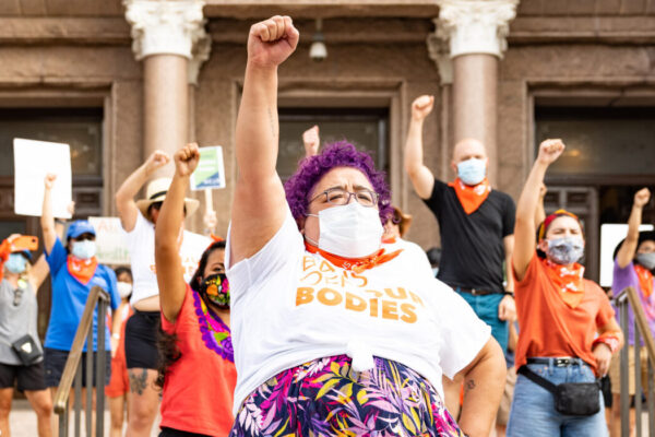 Activists wearing "Bans off our bodies" shirt and throwing fists in the air