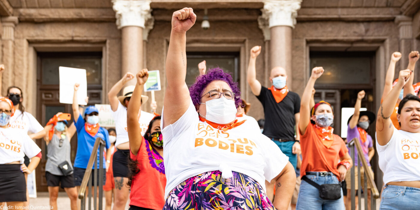 Activists wearing "Bans off our bodies" shirt and throwing fists in the air