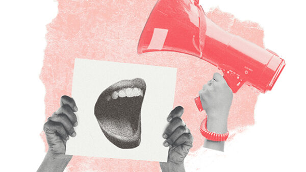 protestor holding up sign, another hand holds up a megaphone