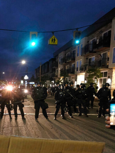 A protester records police in riot gear as they form a wall to push crowds of demonstrators in Portland, Ore., on June 30, 2020, in the wake the murder of George Floyd.
