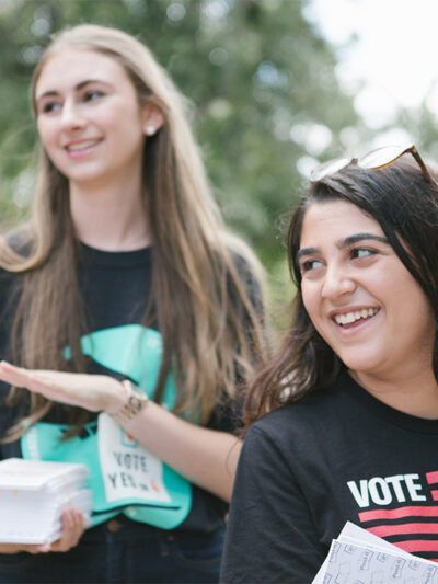Two smiling canvassers carrying voting information.