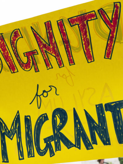 A sign reading "Dignity for Migrants."