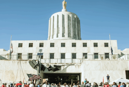 ACLU Oregon 2023 Legislative Session Report cover, a photo of the south entrance of the Oregon State Capitol, with people rallying on the steps