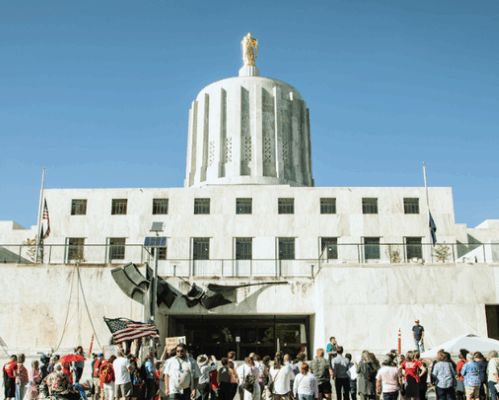 ACLU Oregon 2023 Legislative Session Report cover, a photo of the south entrance of the Oregon State Capitol, with people rallying on the steps