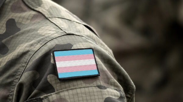 Transgender Pride flag on shoulder of a military camouflage uniform.