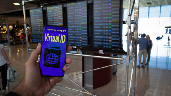 Hand holding a paperless passport virtual ID on smartphone screen with airport timetables as background.