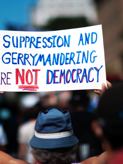 A demonstrator at the March On for Voting Rights in Washington D.C. holds up a sign reading "Suppression and Gerrymandering are Not Democracy".