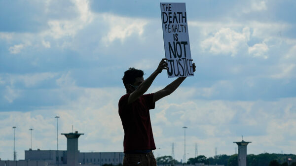A man holding a sign that says "Death Penalty is Not Justice."
