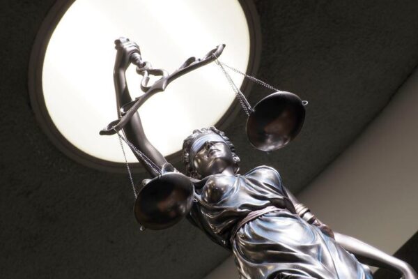 Image of brass statue holding scales in courtroom