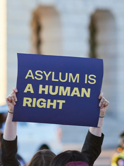 Asylum supporter holding up a sign reading " ASYLUM IS A HUMAN RIGHT".