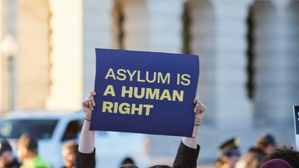 Asylum supporter holding up a sign reading " ASYLUM IS A HUMAN RIGHT".