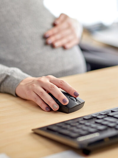 A pregnant worker on a computer at her desk.