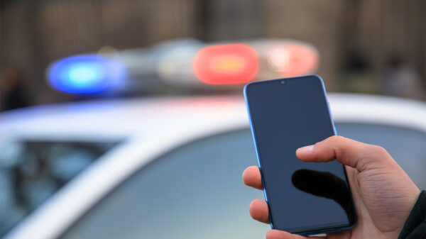 Hand holding phone with police car lights shining in the background.