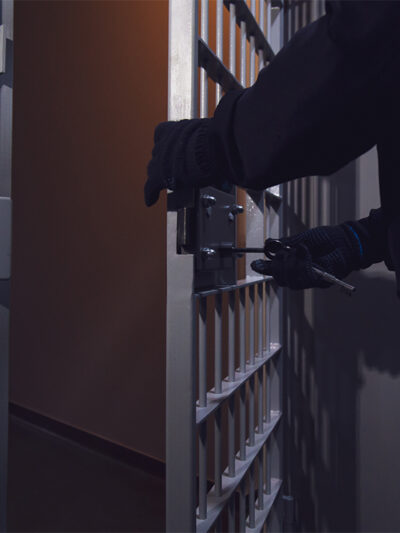 A cell door in a prison being locked by a gloved officer.
