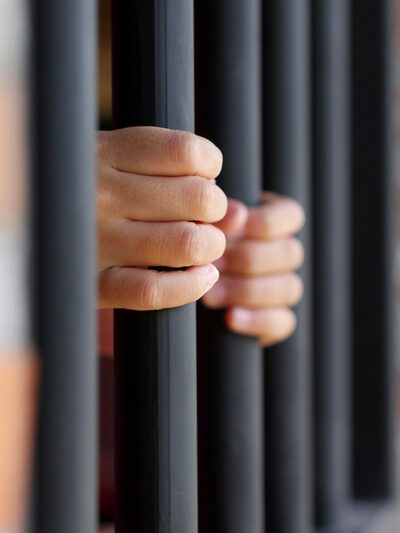 An individual holing on to prison bars.