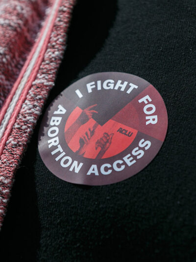 Someone wearing a sticker that says "I Fight For Abortion Access."